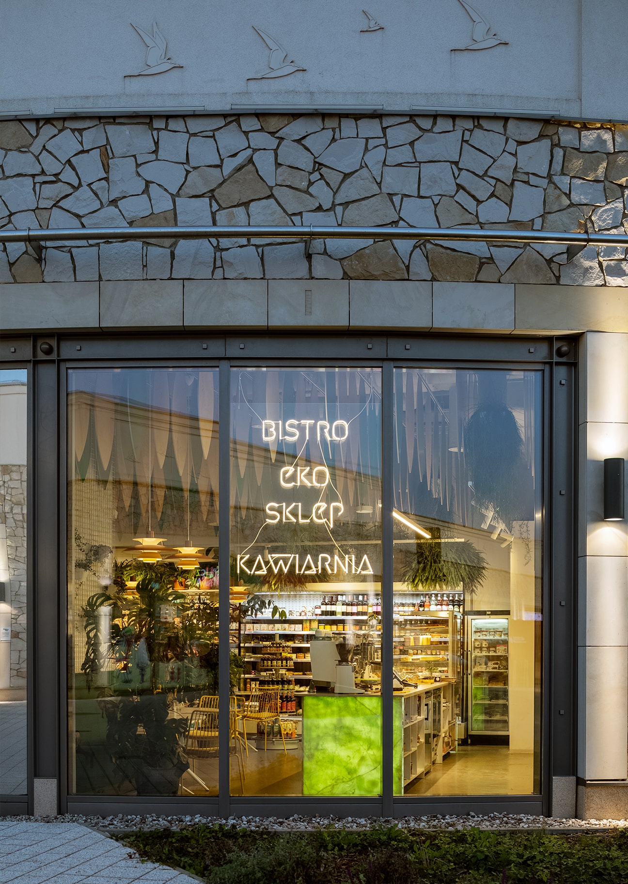 Window with neon sign of Wiele Dobrego on Vogla Square in Warsaw.